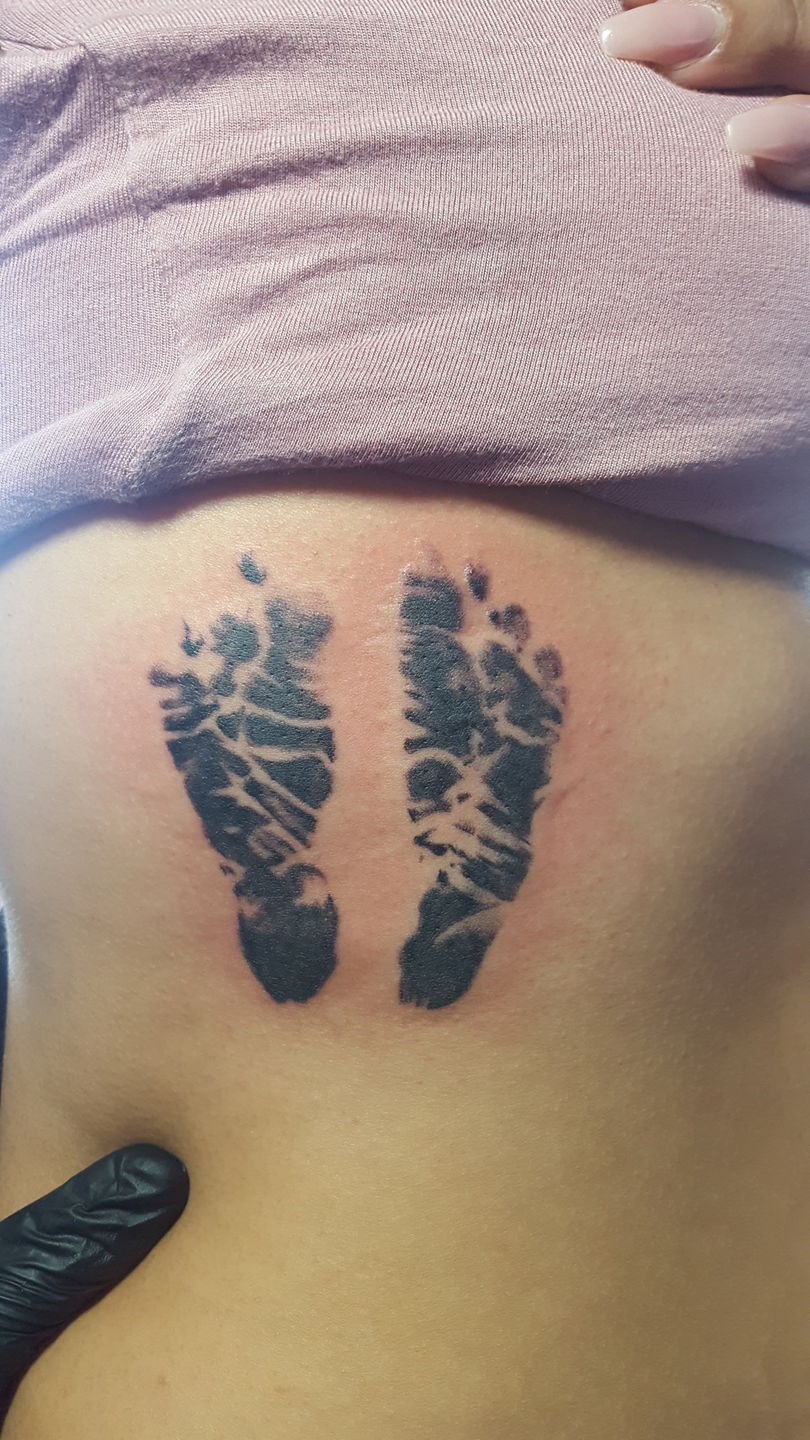 Baby footprints and date tattooed on the inner forearm.